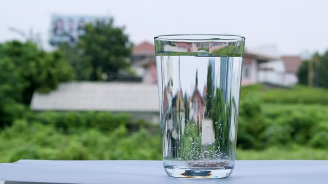 Dropping a tablet of antacid into a glass of water that burst into tiny bubbles in the water.