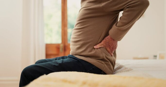 Hands, man and pain in home from back, muscle injury or risk of fatigue for scoliosis in bedroom. Closeup, bad posture and stretching spine for fibromyalgia, osteoporosis and healthcare for arthritis