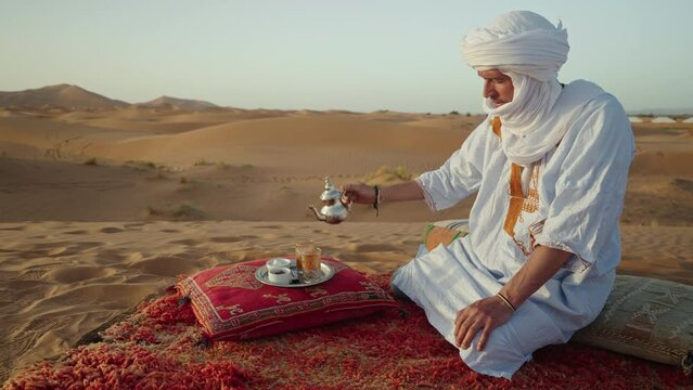 Berber man preparing the traditional moroccan tea in the desert, Morocco