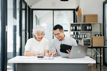 Two business workers talking on tablet and using laptop