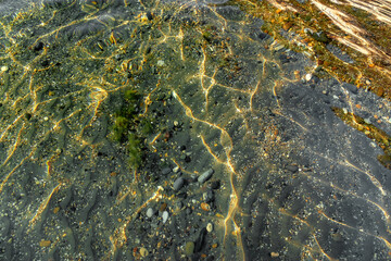 Perfectly clean sea water and the seabed near the shore. View of the seabed near the shore through clear water. Patterns of the sun breaking through crystal clear water on the seabed. 