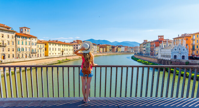 Tourist female in Pisa, Arno river, lamp and buildings reflection. Lungarno view.santa maria della spina