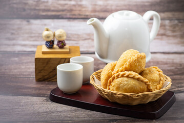 Curry puff, white teapot set isolated on white background. Samosa chicken fried curry bakery, meat, vegetable on wooden table. Yummy pie, Asian street food, Crispy snack eating with tea, coffee bread