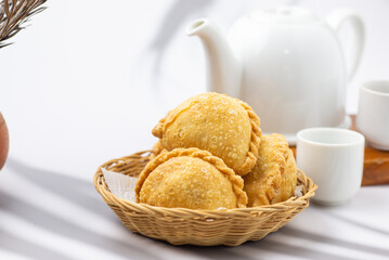 Curry puff, white teapot set isolated on white background. Samosa chicken fried curry bakery, meat, vegetable on wooden table. Yummy pie, Asian street food, Crispy snack eating with tea, coffee bread