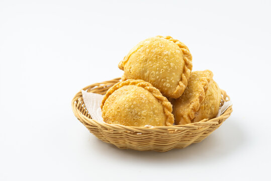 Curry puff on wicker basket isolated on white background. Samosa chicken fried curry dumpling,  meat or vegetable snuffing. Yummy pie, Asian street food, Crispy snack for eating with coffee tea bread