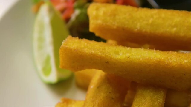 Slow orbit and focus rack of plate with polenta fries, salad and lime