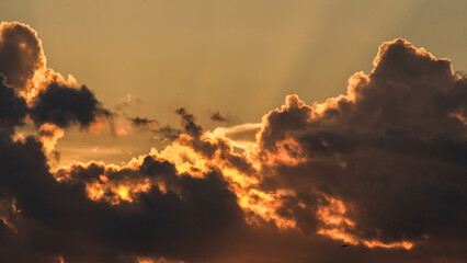 Beautiful dramatic sky with clouds at sunset or sunrise. Sunset sky at dusk in the evening with natural sky background with golden orange clouds.