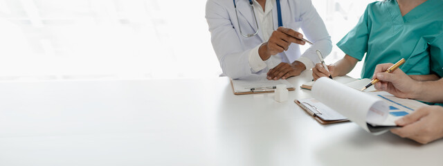 A group of doctors is brainstorming together in a conference room, There was a meeting about major surgery in the hospital, The doctor takes the patient's documents and discusses them with team.