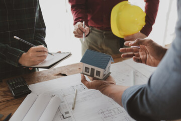 Architects and engineers work together to come up with solutions to house building problems, The property is about to be designed by a group of engineers, Architects are reviewing plans together.