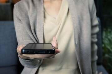 Close-up image of woman holding a mobile phone for technology and lifestyle concept.