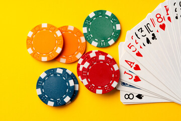 Playing cards and poker chips on yellow background