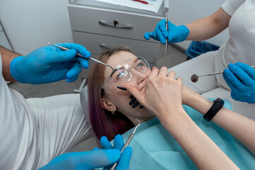 dentist or fear of the doctor of a young female patient who covers her mouth with her hands.
