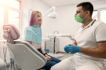 healthy female patient smiling happily in the dental office next to the dentist.