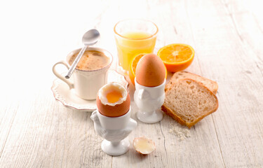 Soft boiled egg with orange juice, bread and coffee cup