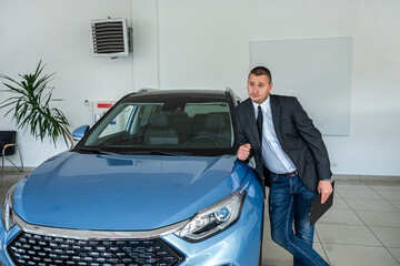  young  salesman in suit waiting for customer at the dealership. purchase car concept