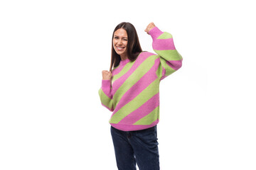 pretty positive cheerful young european brunette woman dressed in a striped pink-green pullover on a white background with copy space