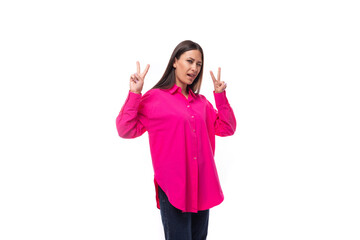 Obraz na płótnie Canvas stylish charming young brunette in a bright pink oversized shirt on a white background with copy space