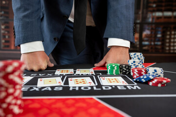 Man in suit hold card and chips play poker at casino - obrazy, fototapety, plakaty