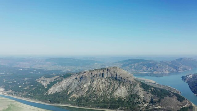 Aerial view of a mountain top, surrounded by a river and a big blue sky