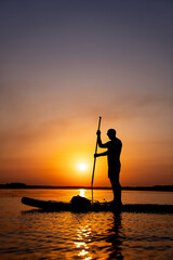 A man standing on top of a boat in the water. A Man Standing on Top of a Boat, Enjoying the Serene Waters