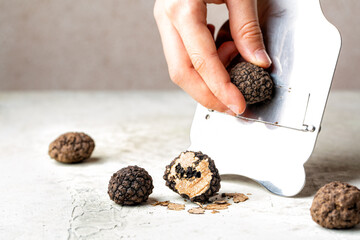 Hands grating delicious black truffles black italian truffle, Tuber Aestivum with special slider or...