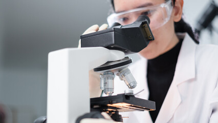 A geologist or archaeologist is using microscope to check rock or mineral sample in paleontology, archaeological and geological or mining laboratory. Concept of fossil research or soil experiment.