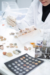 Close up of geologist or archaeologist is selecting and choosing sample of rock, stone or mineral in paleontology, archaeological and geological or mining laboratory. Concept of ground fossil research