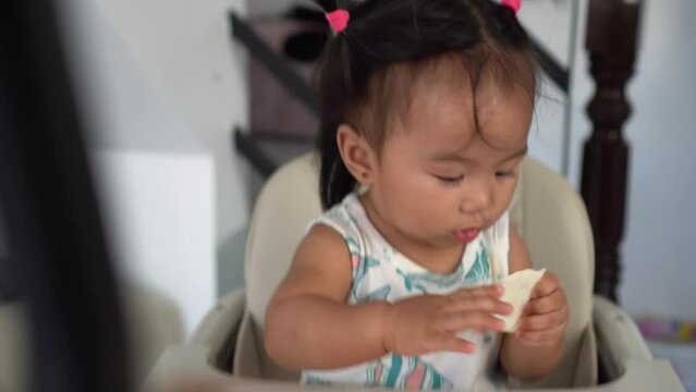 Cute baby girl enjoying a white biscuit