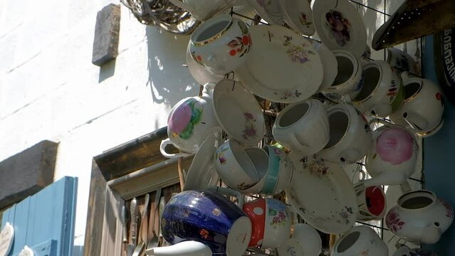 Multicolored faience and porcelain cups and mugs on wall of cafe shop