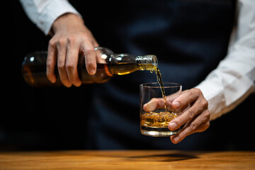 Barman pouring whiskey whiskey glass..