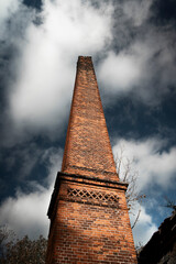 old industrial brick chimney huge tall clouds blue sky, abandoned beauty