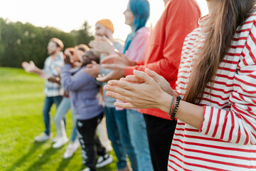 Portrait of group of positive multiracial friends wearing colorful clothes clapping hands
