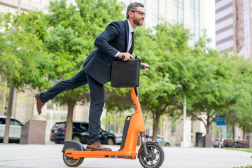 Businessman in suit races to meeting on his electric scooter. Scooter saves day for late businessman. Business man avoids being late with scooter. Businessman avoids traffic with help of scooter.