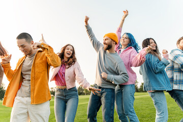Group of attractive multiethnic friends dancing having fun meeting in park. Concept of celebration