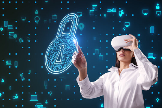 Attractive young european businesswoman with VR glasses pointing at creative padlock hologram on blue background with various icons. Digital safety and security concept.