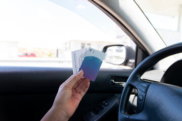Hand in the card holding a card and a ticket for the highway. Concept taxes and expenses are too...