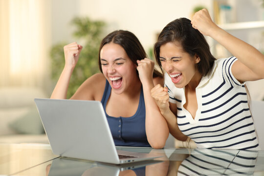 Two excited friends celebrating news on laptop