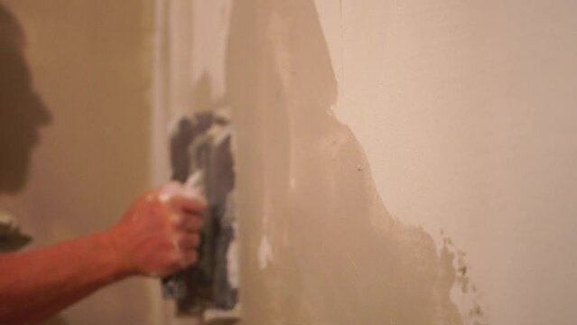Male builder use metal spatula for putty walls, repairman filling spatula with spackling paste and covering cement wall surface. Builder leveling wall and angle Renovation work in Residential Premises