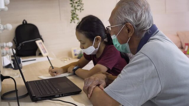 Asian grandfather and young kid study in a bedroom