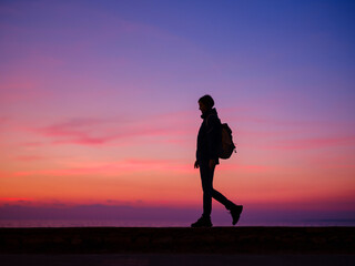 Woman tourist against colorful sunset sky. Travel, tourism concept. Active lifestyle.