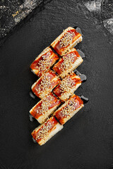 Sushi with eel, cream cheese and omelet on a black background. Close-up. Photo for the menu