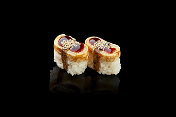 Nigiri sushi with Japanese omelette and unagi sauce on a black background.