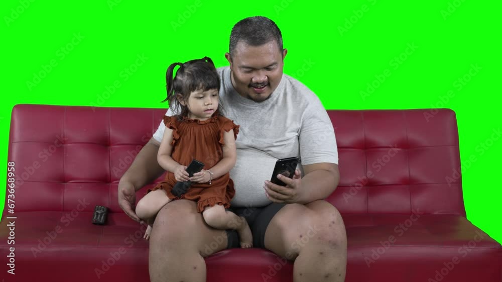 Wall mural 4k footage of father and daughter watching online video streaming on a mobile phone