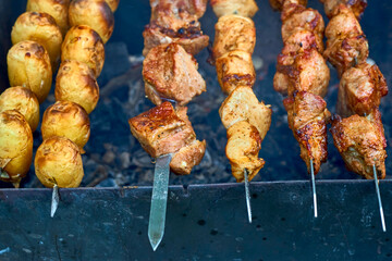 Marinated meat and potatoes on skewers, grilled over hot coals