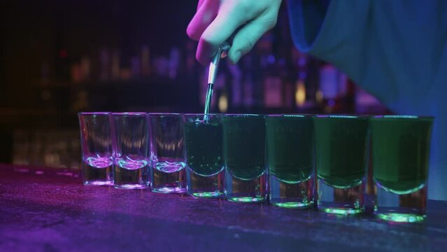 A Bartender's Artistry: Pouring Drinks into a Row of Glasses