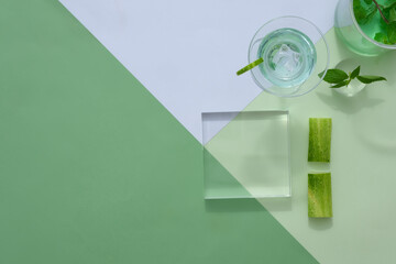 Minimal style with pedestal for display cosmetic product from cucumber ingredient. Fresh cucumber slices decorated with transparent podium and glass cups on color background.