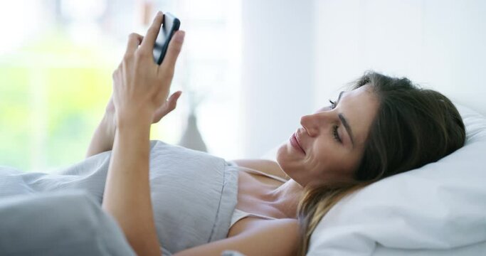Woman, happy and scroll phone in bed for reading funny social media notification, chat or mobile app at home. Cellphone, typing and search meme, contact and download network in bedroom in the morning