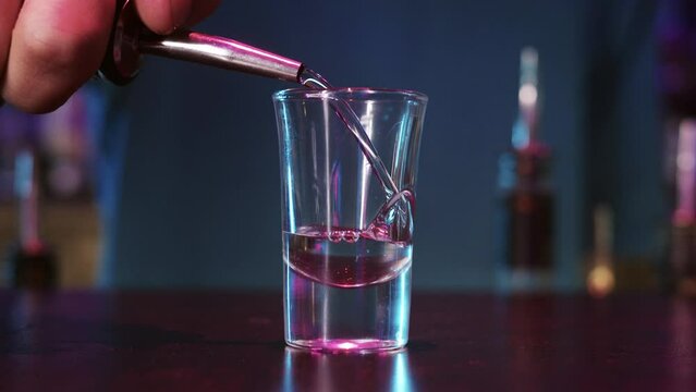 A Bartender Skillfully Pouring a Colorful Cocktail into a Glass