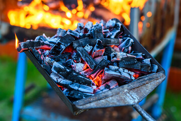Szufla z rozżarzonym węglem na tle ognia na grillu