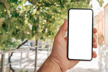 Man holding smartphone with blank white mockup screen in house back yard